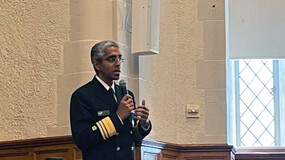 Surgeon General Vivek Murthy standing with microphone