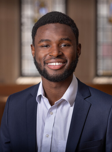 Chaka Tellem in a dark blazer and light shirt in a classroom with stained glass