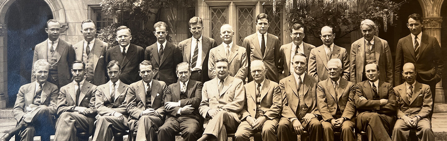 A group of faculty members seated in the courtyard