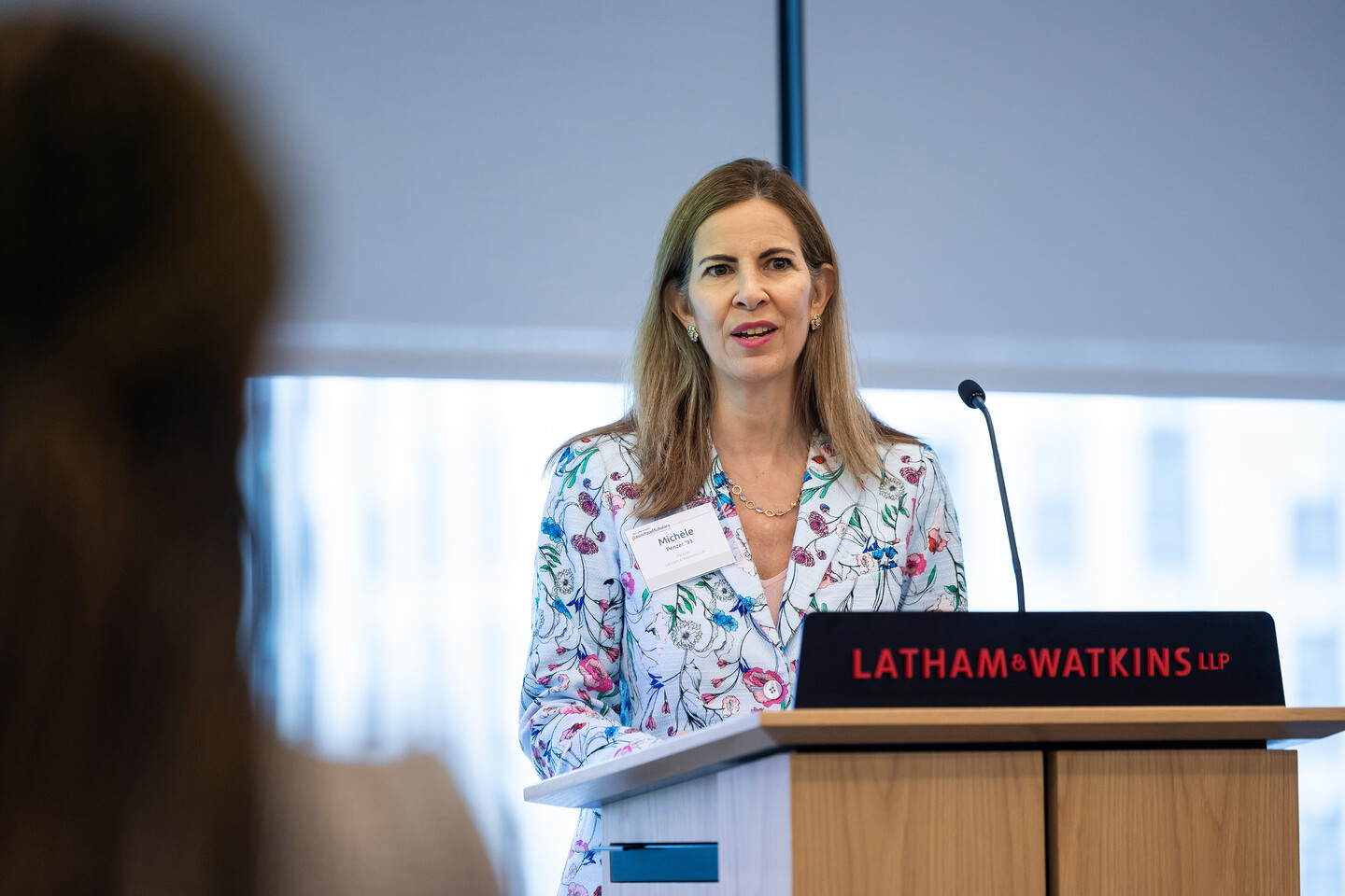 woman speaking at a podium that says Latham & Watkins