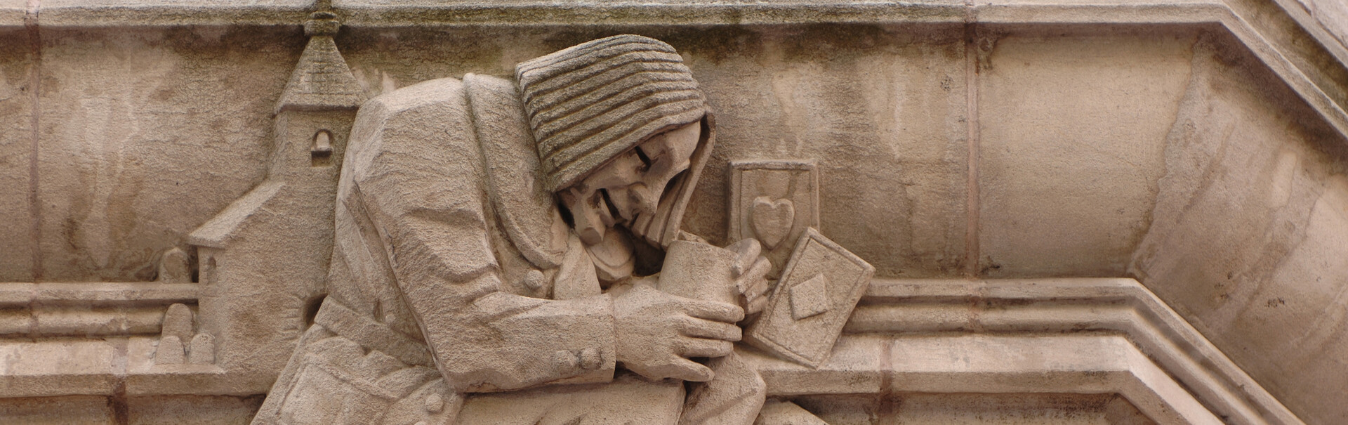 stonework detail of a man playing cards